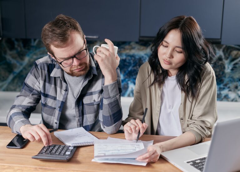 Couple reviewing household bills and expenses together at the kitchen table